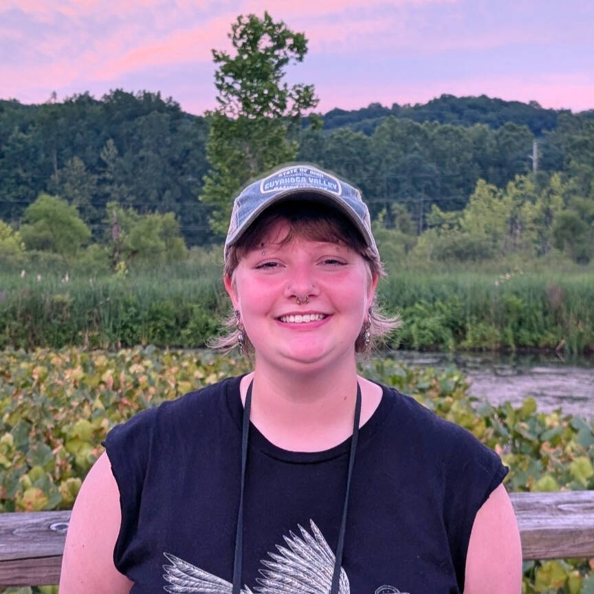 Smiling blonde woman wearing a hat against a nature background